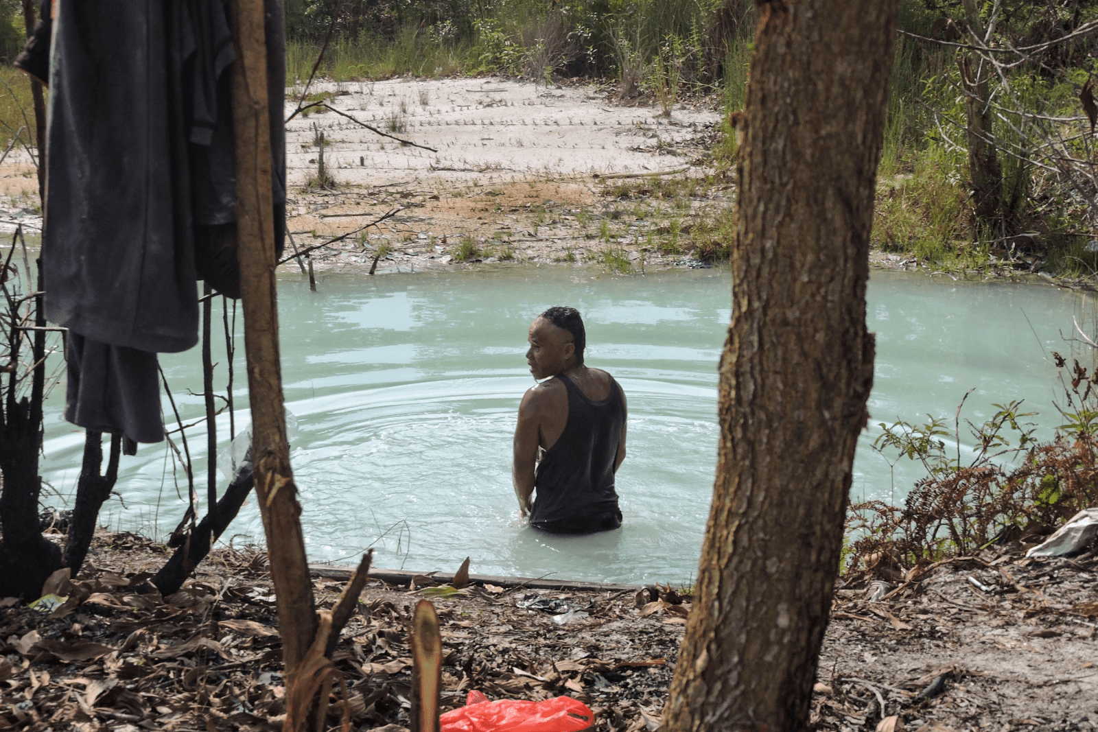 Seorang penambang rakyat sedang mandi di kolam bekas tambang. Buaya sering kali menampakkan diri di kolam tersebut dan sekitarnya. | Foto: Bayu Nanda/Garda Animalia